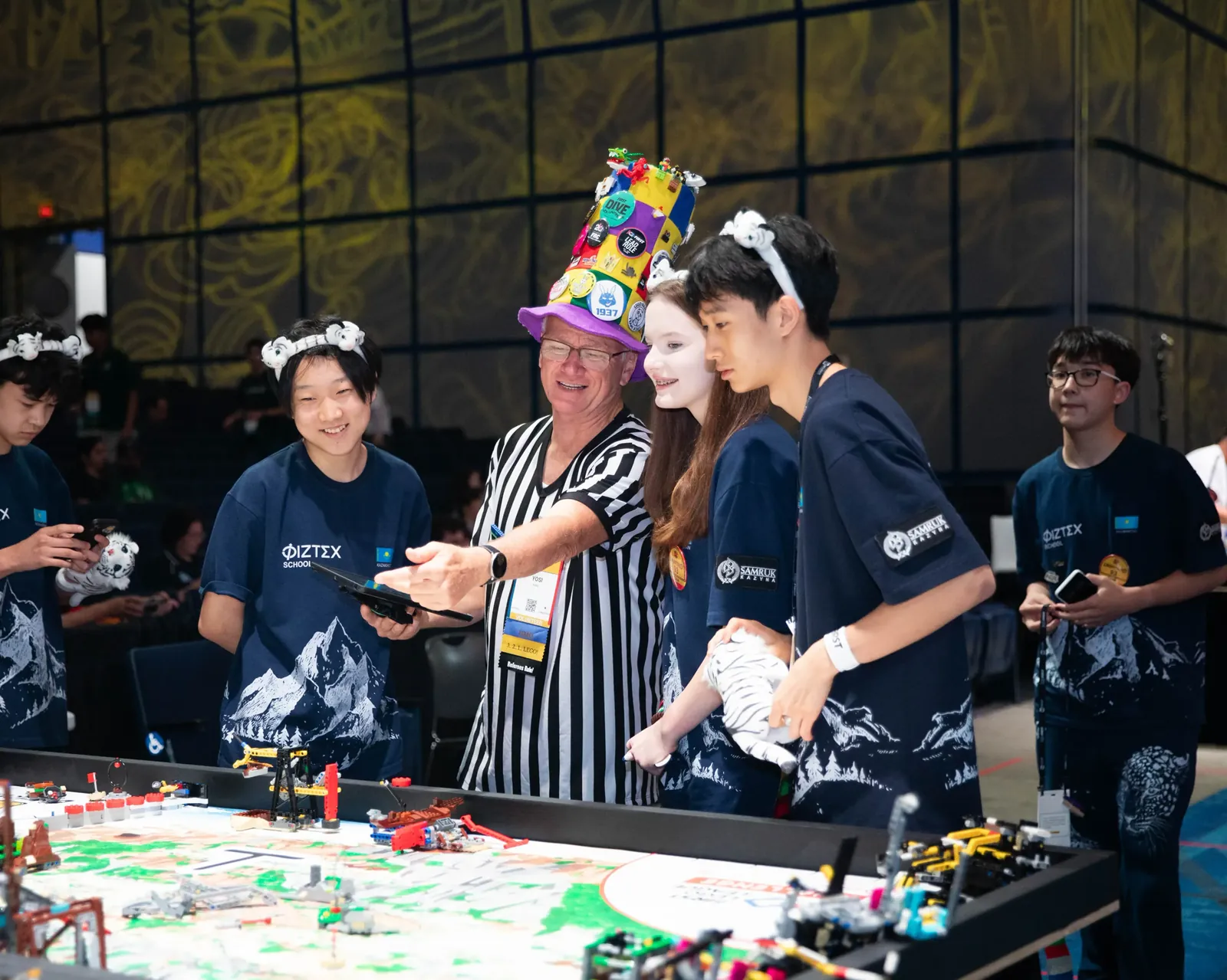 FIRST LEGO League төрешісі ойын алаңының жанында Қазақстан командасымен заезды талқылап тұр